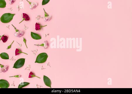 Muster aus grünen Blättern, Rosen, Zigeunern und Nelkenblüten auf einem rosa Pastellgrund. Festliches Konzept mit Kopierfläche. Stockfoto