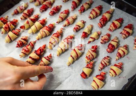 Großmutter, die vor dem Backen in der Küche im Innenbereich handgemachte leckere Butter mit Obst- und Beerenmarmelade auf dem Backblech zubereitet. Rolled Spin hausgemacht Stockfoto