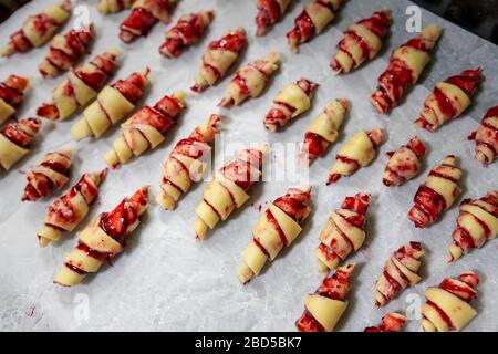 Großmutter, die vor dem Backen in der Küche im Innenbereich handgemachte leckere Butter mit Obst- und Beerenmarmelade auf dem Backblech zubereitet. Rolled Spin hausgemacht Stockfoto