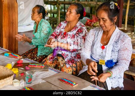 Horizontaler Blick auf Menschen, die religiöse Dekorationen mit Reispaste in einem Tempel in Bali, Indonesien, machen. Stockfoto