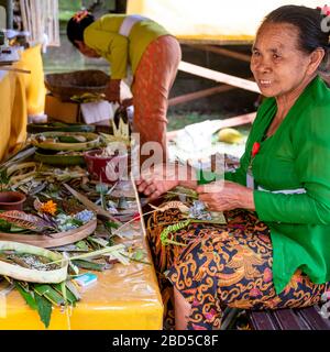 Viereckiges Porträt der Damen, die in einem Tempel in Bali, Indonesien, in Dekorationen eindringen. Stockfoto