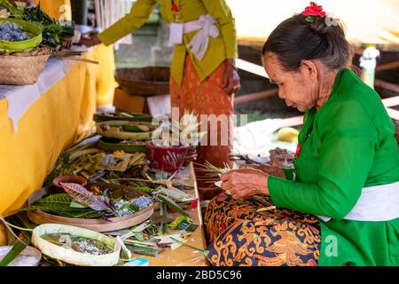 Horizontaler Blick auf Damen, die traditionelle Dekorationen in einem Tempel in Bali, Indonesien, machen. Stockfoto