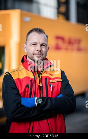 Gelsenkirchen, Deutschland. April 2020. Nino Moldmann, DHL Paketzusteller, steht in Gelsenkirchen-Buer vor seinem Auto. Er ist einer der "Helden der Koronakrise" und arbeitet in einem systemwichtigen Beruf. Kredit: Fabian Strauch / dpa / Alamy Live News Stockfoto