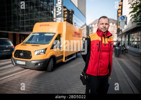 Gelsenkirchen, Deutschland. April 2020. Nino Moldmann, DHL Paketzusteller, steht in Gelsenkirchen-Buer vor seinem Auto. Er ist einer der "Helden der Koronakrise" und arbeitet in einem systemwichtigen Beruf. Kredit: Fabian Strauch / dpa / Alamy Live News Stockfoto