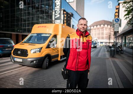 Gelsenkirchen, Deutschland. April 2020. Nino Moldmann, DHL Paketzusteller, steht in Gelsenkirchen-Buer vor seinem Auto. Er ist einer der "Helden der Koronakrise" und arbeitet in einem systemwichtigen Beruf. Kredit: Fabian Strauch / dpa / Alamy Live News Stockfoto