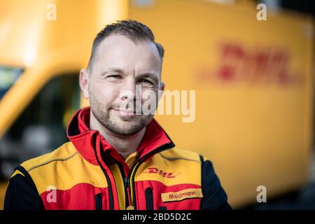 Gelsenkirchen, Deutschland. April 2020. Nino Moldmann, DHL Paketzusteller, steht in Gelsenkirchen-Buer vor seinem Auto. Er ist einer der "Helden der Koronakrise" und arbeitet in einem systemwichtigen Beruf. Kredit: Fabian Strauch / dpa / Alamy Live News Stockfoto