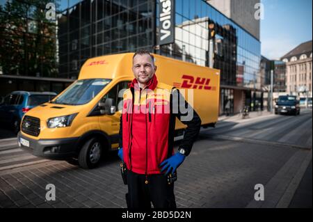 Gelsenkirchen, Deutschland. April 2020. Nino Moldmann, DHL Paketzusteller, steht in Gelsenkirchen-Buer vor seinem Auto. Er ist einer der "Helden der Koronakrise" und arbeitet in einem systemwichtigen Beruf. Kredit: Fabian Strauch / dpa / Alamy Live News Stockfoto