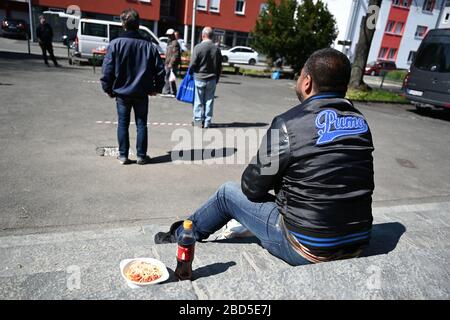 Friedrichshafen, Deutschland. April 2020. 07. April 2020, Baden-Württemberg, Friedrichshafen: Eine bedürftige Person isst auf den Stufen der katholischen Kirche St. Peter Canisius einen Teil Spaghetti-Bolognese. Fast 30 bedürftige Menschen erhalten zur Mittagszeit eine kostenlose Mahlzeit. Neben der städtischen Entkräuselei wurde die Armenspeisung auch von den "Herberge" - einer Einrichtung für Obdachlose - und dem Streetworker-Verein Arkade organisiert. Finanziert wurde das Projekt unter anderem durch Spenden aus der Stadt, dem Landkreis und der Neuolischen Kirche. Viele Einrichtungen, in denen Obdachlose normalerweise empfangen wurden Stockfoto