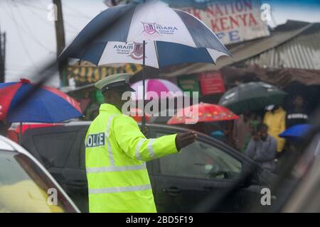 Die Polizei, die den Verkehr während der Hauptverkehrszeit am Morgen, während eines Regensturms, in Nairobi, Kenia, Kenia, zusammen mit anderen Ländern in E.Afrika lenkt, hat h Stockfoto