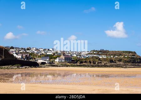 Ruhiger Strand bei Ebbe mit Wohnwagen im Ferienpark am Hang, der sich in nassem Sand widerspiegelt. Benllech, Insel Anglesey, Nordwales, Großbritannien Stockfoto