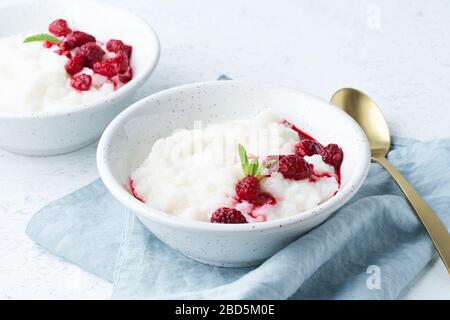 Reispudding, Seitenansicht. Gesundes vegetarisches Frühstück mit Kokosmilch, Himbeere, skandinavisch Stockfoto