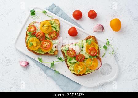 Avocado Toast mit Kirschtomaten und Kräutern, Frühstück, Draufsicht Stockfoto