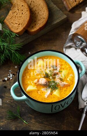 Norwegische Küche. Suppe mit Sahne und Lachs auf einem rustikalen Holztisch. Stockfoto