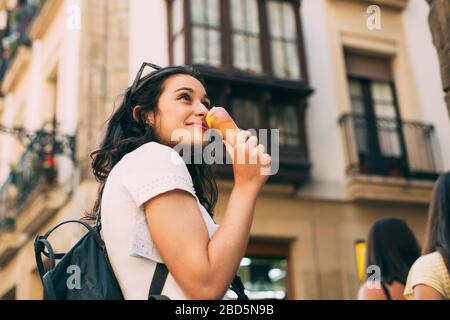 Junge Touristenfrau, die beim Besuch einer europäischen Stadt Eis genießt und isset Stockfoto