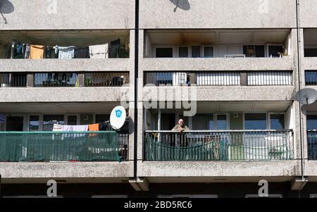 Leith, Edinburgh, Schottland, Großbritannien. April 2020. In der dritten Woche des landesweiten Coronavirus Sperrlebens in Leith geht es weiter, obwohl die Straßen meist verlassen sind und Geschäfte geschlossen sind. Abgebildet; älterer Mann auf Balkon in seiner Wohnung in Kabeln Wynd House Apartmentblock. Stockfoto