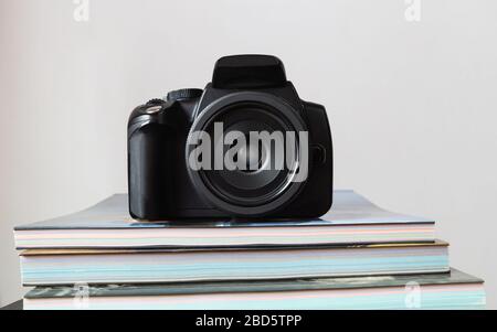 Digitale schwarze Kamera (DSLR) auf bunten, gestapelten Büchern Stockfoto