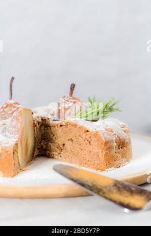 Köstliche Tortenscheibe mit Birne, Ingwer und Zimt auf einem Teller in einer dunklen Küchentheke. Stockfoto