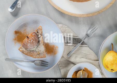 Köstliche Tortenscheibe mit Birne, Ingwer und Zimt auf einem Teller in einer dunklen Küchentheke. Stockfoto