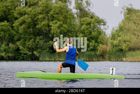 Kanueinzelmännchen paddeln im Kanusprint auf See Stockfoto