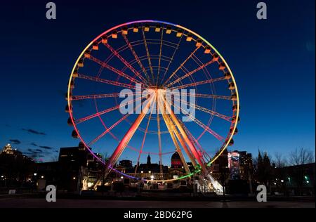 Montreal, Kanada. April 2020. Das große Rad im alten Hafen von Montreal, Quebec, Kanada, wird am Montag, 6. April 2020 in Regenbogenfarben beleuchtet, da Coronavirus COVID-19-Fälle in Kanada und auf der ganzen Welt aufsteigen. Kredit: Graham Hughes/Alamy Live News Stockfoto