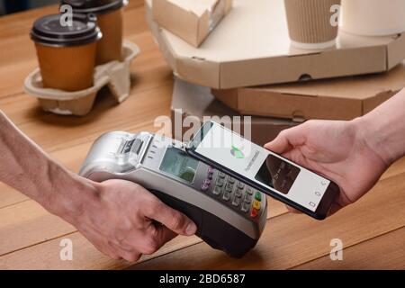 Mann, der mit seinem Telefon für Pizza und Kaffee bezahlt Stockfoto