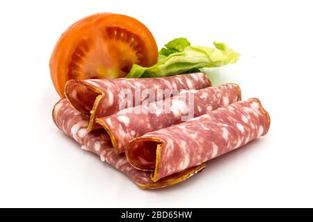 Scheibe Gaumais Wurst auf weißem Grund mit einer halben Tomate und einem Salatblatt Stockfoto
