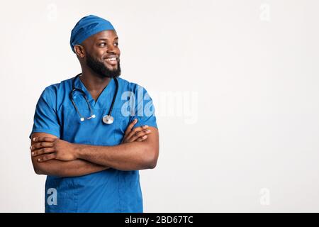 Junger afrikanischer Arzt in blauer Uniform mit Blick auf den leeren Raum Stockfoto
