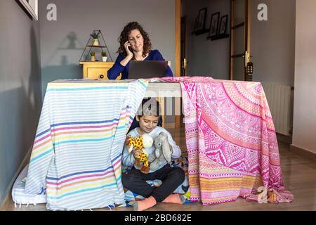 Mutter arbeitet zu Hause, während ihr Sohn spielt Stockfoto