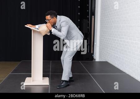 Betont afroamerikanische Unternehmer atmen mit Papiertüten und haben Panikattacken während der Geschäftskonferenz im Büro Stockfoto