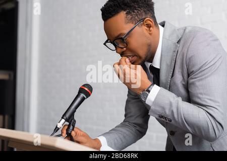 Nervöser afroamerikanischer Sprecher beißt Nägel während der Geschäftskonferenz im Büro Stockfoto