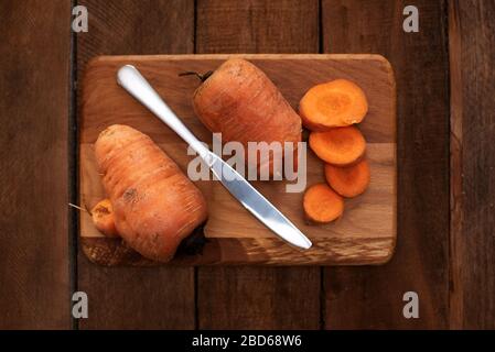 Trendige hässliche Bio-Karotte vom Hausgarten-Bett auf dem Barnholztisch. Farbtonierungseffekt angewendet Stockfoto