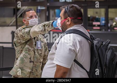 Hawaii Army National Guard Spc. James Kamaka, der Passagiere auf dem Daniel K. Inouye International Airport am 6. April 2020 in Honolulu, Hawaii abreist. Soldaten unterstützen das Flughafenfeuerpersonal bei der Überprüfung von 100 % der Reisenden, die ankommen und abreisen, um Reisen zwischen den Inseln einzubeziehen. Stockfoto