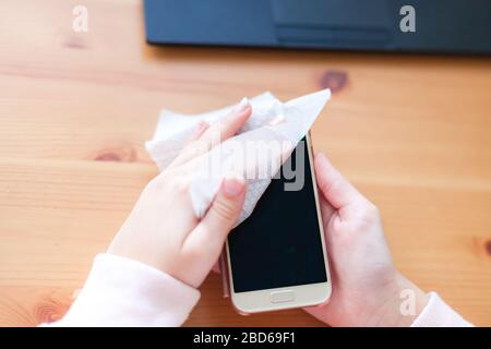 Frauenhände wischen ihr Handy mit einer antibakteriellen Serviette, Virenschutz Stockfoto