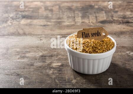 Golden Leinsamen in Weiß Schüssel auf Holztisch. Platz kopieren Stockfoto