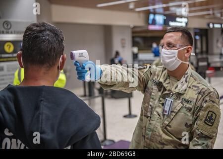 Hawaii Army National Guard Spc. James Kamaka, der Passagiere auf dem Daniel K. Inouye International Airport am 6. April 2020 in Honolulu, Hawaii abreist. Soldaten unterstützen das Flughafenfeuerpersonal bei der Überprüfung von 100 % der Reisenden, die ankommen und abreisen, um Reisen zwischen den Inseln einzubeziehen. Stockfoto