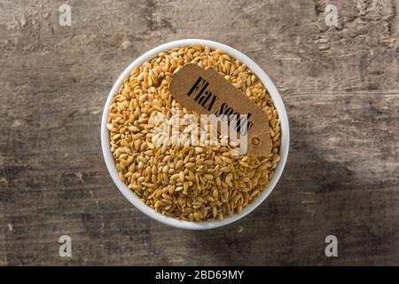 Golden Leinsamen in Weiß Schüssel auf Holztisch. Ansicht von oben Stockfoto