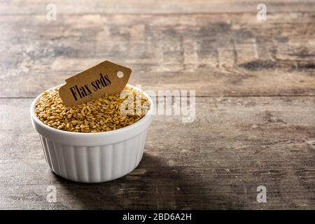 Golden Leinsamen in Weiß Schüssel auf Holztisch. Platz kopieren Stockfoto