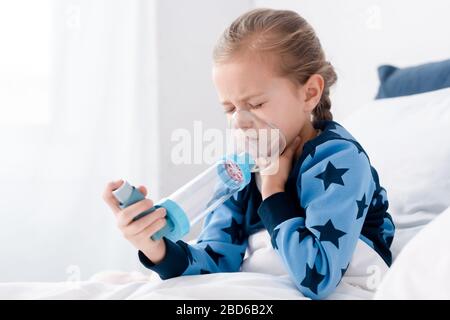 Krankes Kind mit geschlossenen Augen mit Inhalator mit Abstandshalter Stockfoto