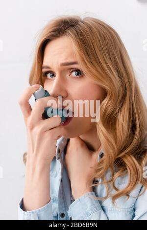 Schöne und asthmatische Frau mit Inhalator und Blick auf die Kamera Stockfoto