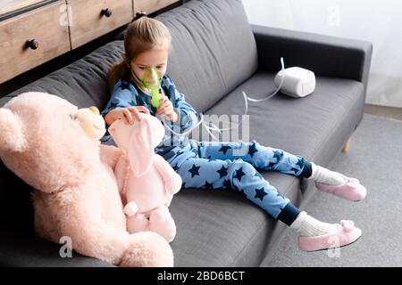 Asthmatisches Kind mit Kompressor-Inhalator in der Nähe von Softspielzeug Stockfoto