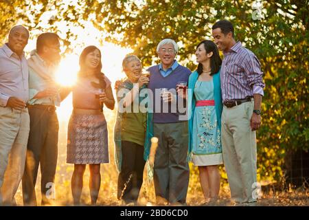 Lächelnd Gruppe von Freunden feiern mit Getränken in einem Hinterhof. Stockfoto