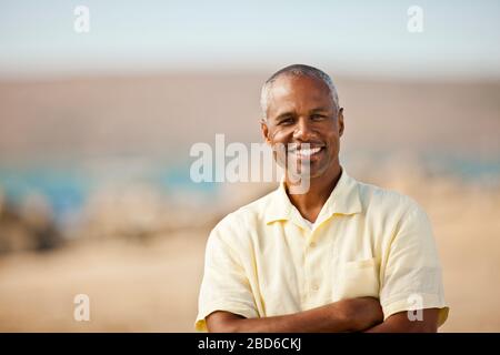 Porträt eines lächelnden Mannes, der an einem Strand steht. Stockfoto
