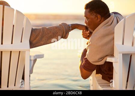 Glücklicher älterer Mann, der die Hand seiner Frau liebevoll küsst. Stockfoto