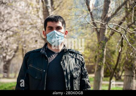 COVID-19. Junger Mann in sterilen Schutz medizinische Gesichtsmaske im Freien. Coronavirus-Konzept. Stockfoto