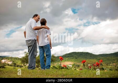 Reifer Mann, der mit seinem jungen Sohn durch das Feld geht. Stockfoto