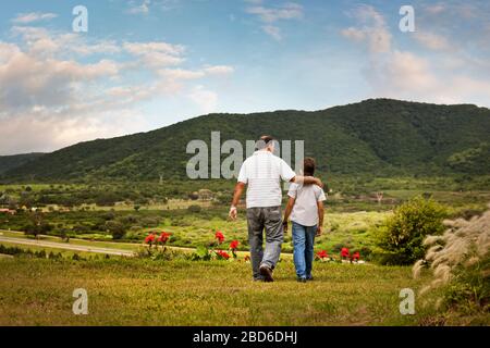 Reifer Mann, der mit seinem jungen Sohn durch das Feld geht. Stockfoto