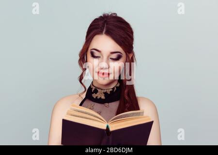 Mädchen mit Buch. Closeup brünette schöne junge Frau ziemlich glücklich lesen eine Liebesromanze Teenager-Mädchen isoliert hellgrün grau grauen Hintergrund Wand Stockfoto