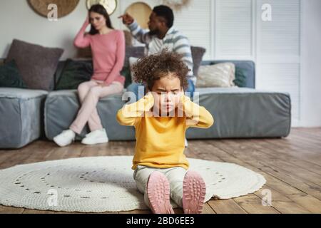 Mädchen sitzt auf dem Boden, schließt ihre Ohren und Augen Stockfoto