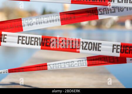 Nahaufnahme des Absperrbandes "Feuerwehr - Sperrzone" (Feuerwehr, Sperrzone). Wird verwendet, um einen Steg zu schließen (aufgrund von Einschränkungen für Covid-19). Stockfoto