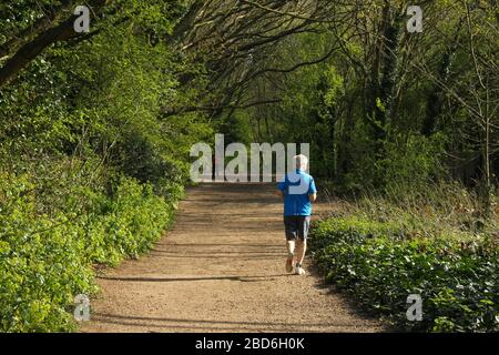 Wanstead Park, London, Großbritannien - 07. April 2020: Ein Mann jogiert im Wanstead Park und beobachtet die soziale Distanzierung an einem sonnigen Dienstagnachmittag während des UK Lockdown. Die Regierung hat der Öffentlichkeit geraten, aufgrund der Covid-19-Pandemie zu Hause in ganz Großbritannien zu bleiben, aber für wichtige Reisen für Grundlagen und Bewegung. Fotos: David Mbiyu/Alamy Live News Stockfoto